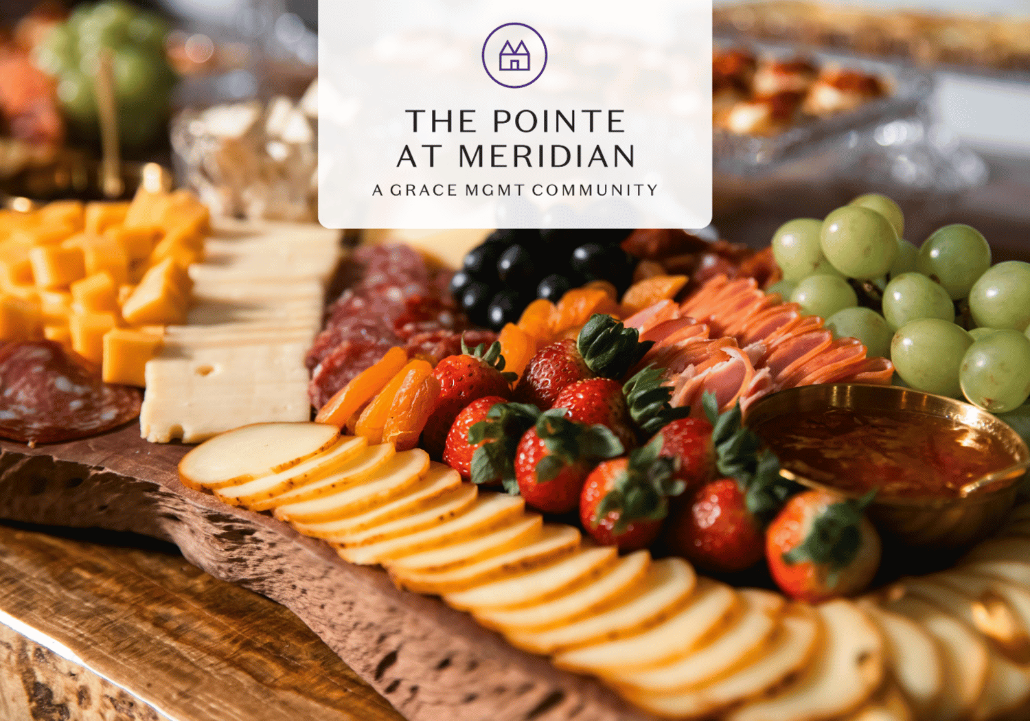 Charcuterie board with cheese, fruit, and meats on a wooden board, overlaid with The Pointe at Meridian logo card.
